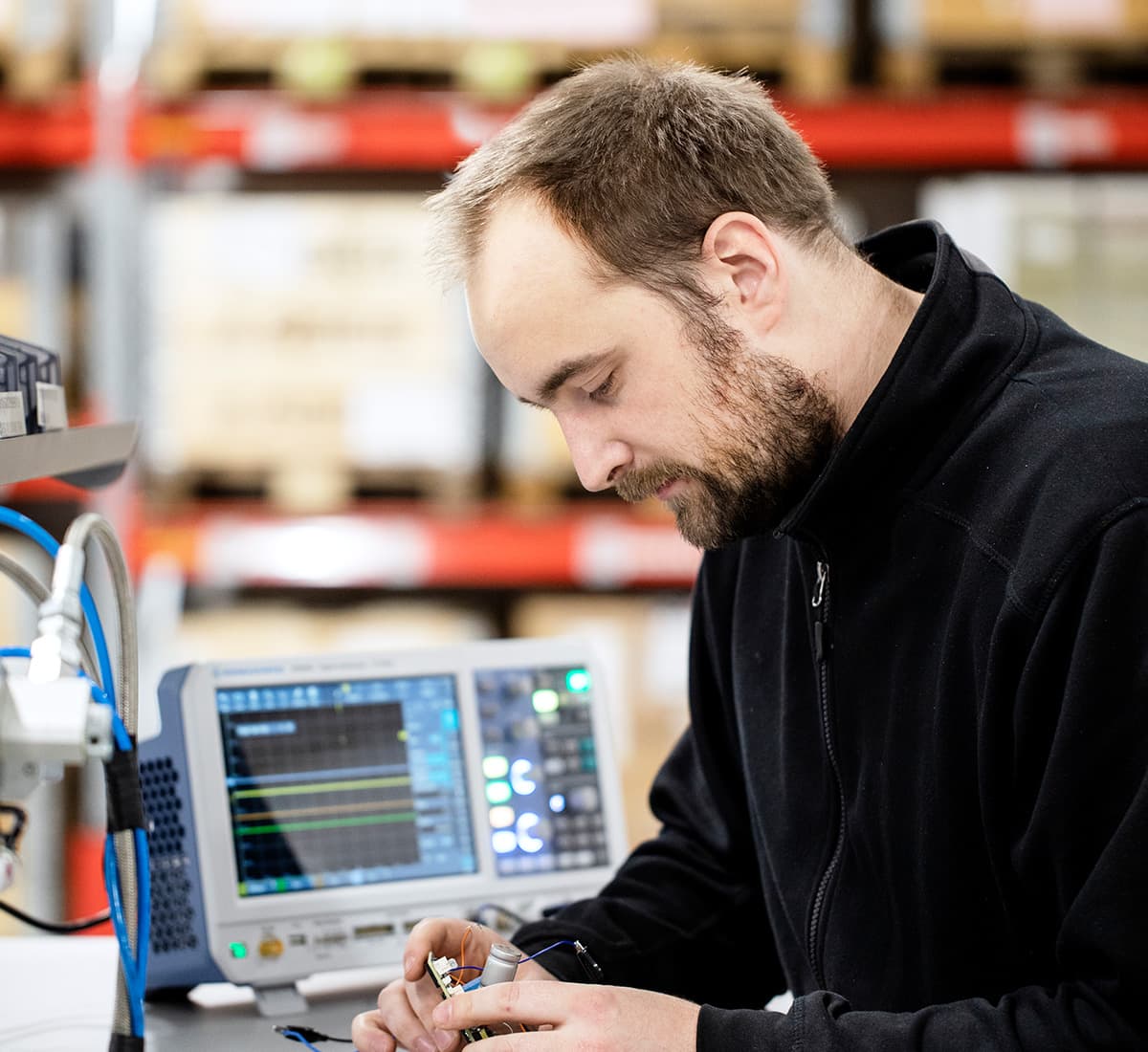 An employee at Backer are testing a circuit board with testing equipment